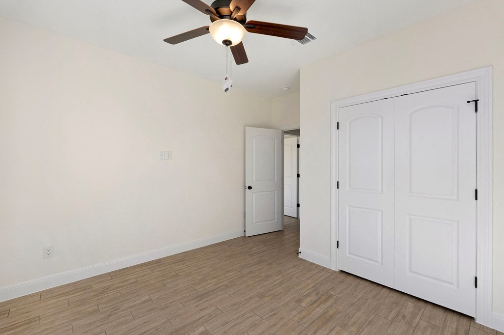 a living room with white walls and a ceiling fan