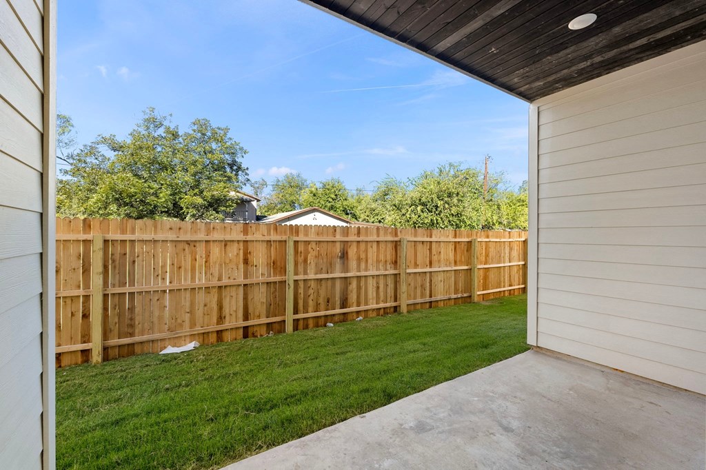 a backyard with a wooden fence and a yard with grass