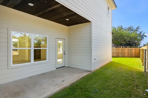 the entrance to a home with a patio and grass