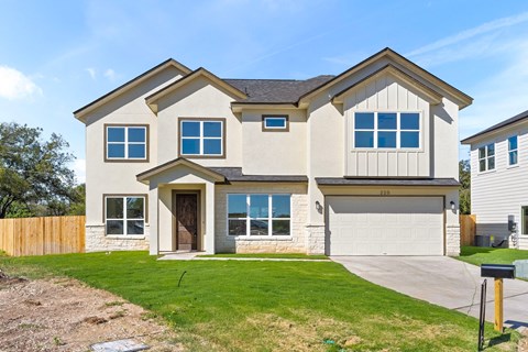 a beige house with a garage door and a lawn
