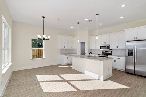 a large kitchen with white cabinets and stainless steel appliances