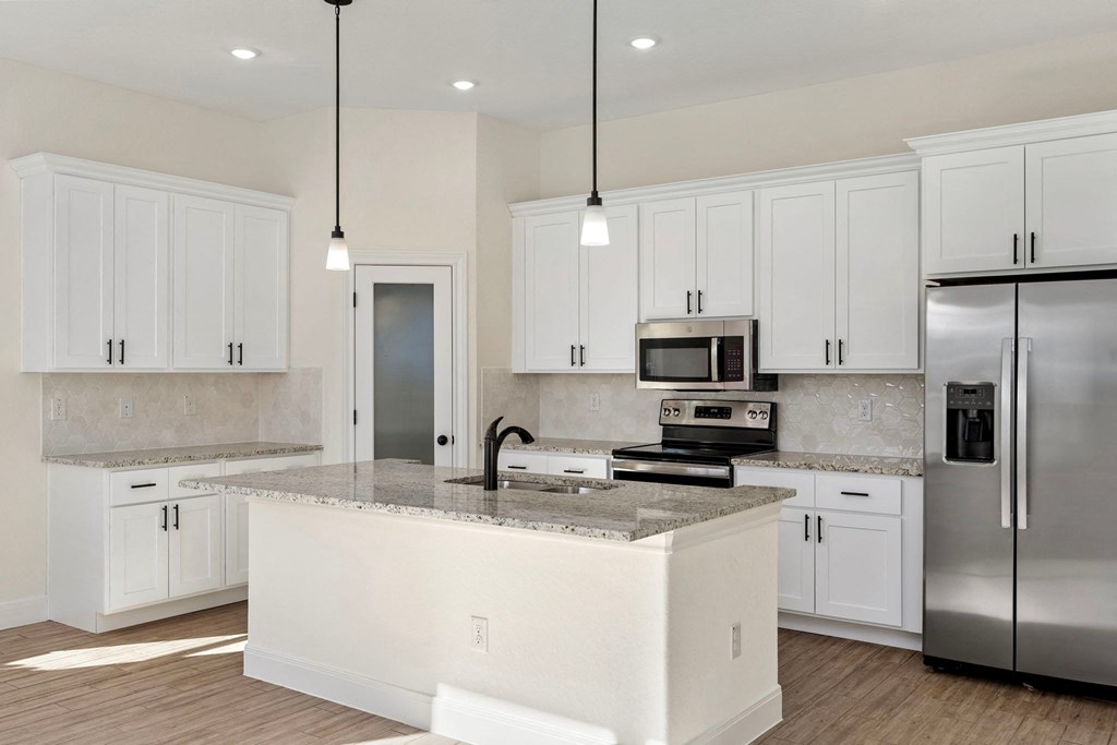 a large kitchen with white cabinets and stainless steel appliances