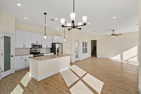 an open kitchen and living room with white cabinets and a large island