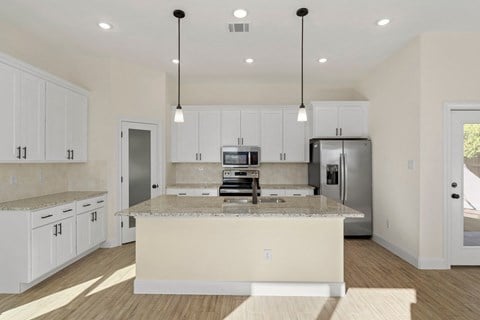 a kitchen with white cabinets and a marble counter top