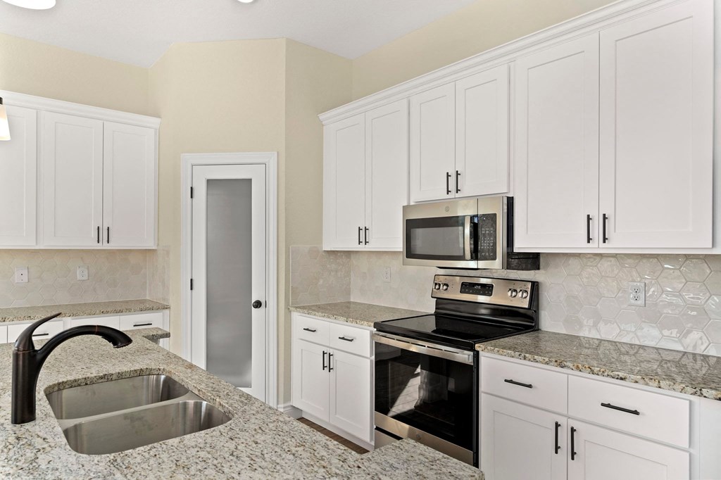 a kitchen with granite counter tops and white cabinets