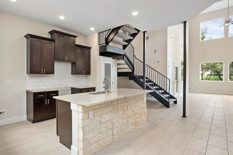 a large kitchen with a marble counter top and a staircase