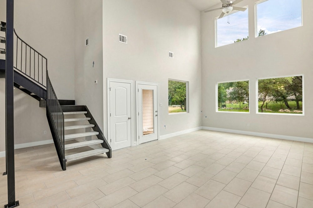a large empty living room with a staircase and a door