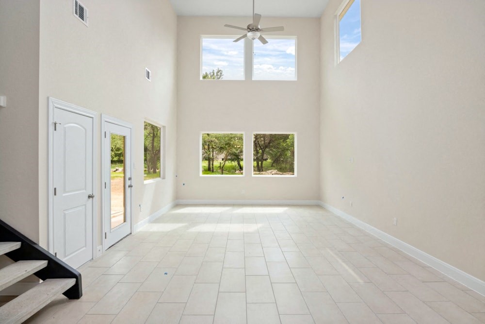 an empty living room with a ceiling fan and windows
