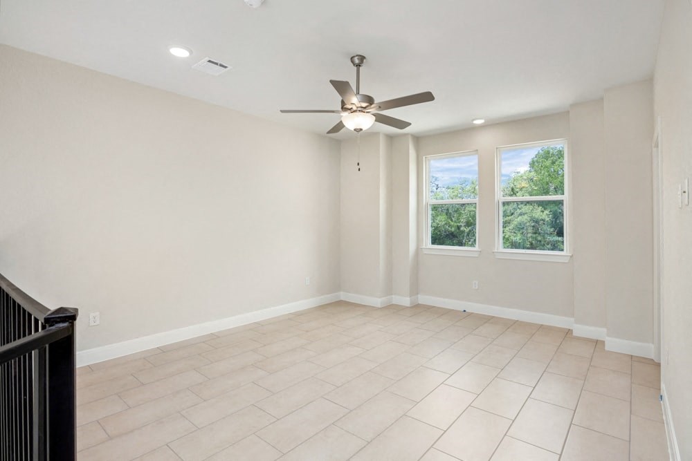 an empty living room with a ceiling fan and a window