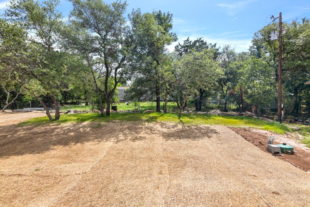 a dirt field with trees and a bench in the middle