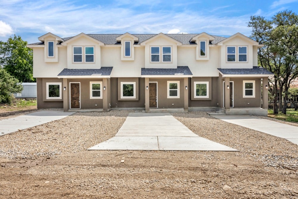 a beige house with a driveway and a lot of gravel