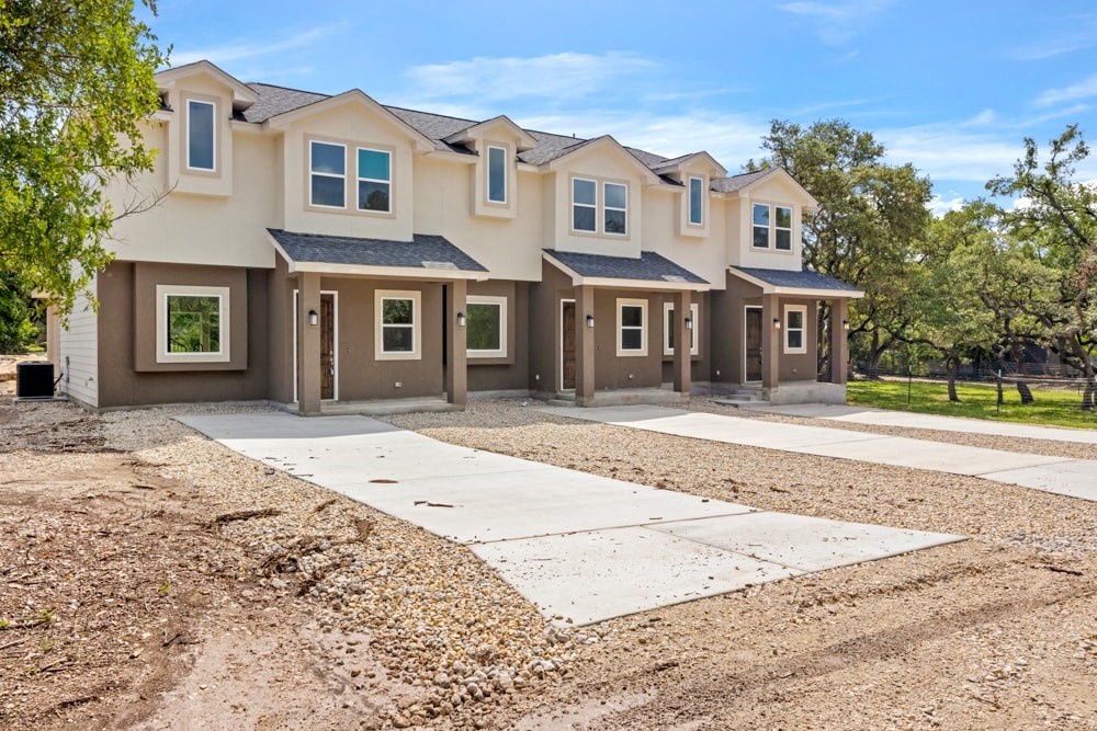 a house with a driveway and a yard with gravel and trees