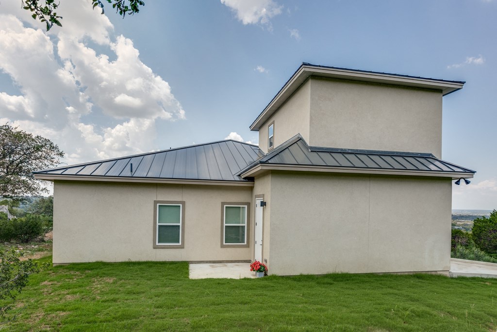 a white house with a gray roof and a green lawn