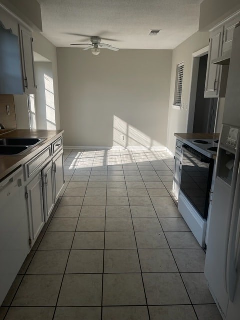 A kitchen with white cabinets and a tile floor.