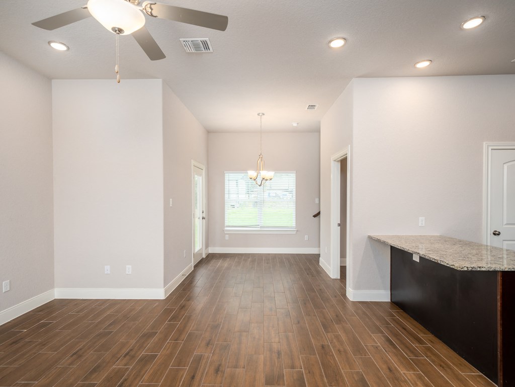 an empty living room with hardwood floors and a ceiling fan