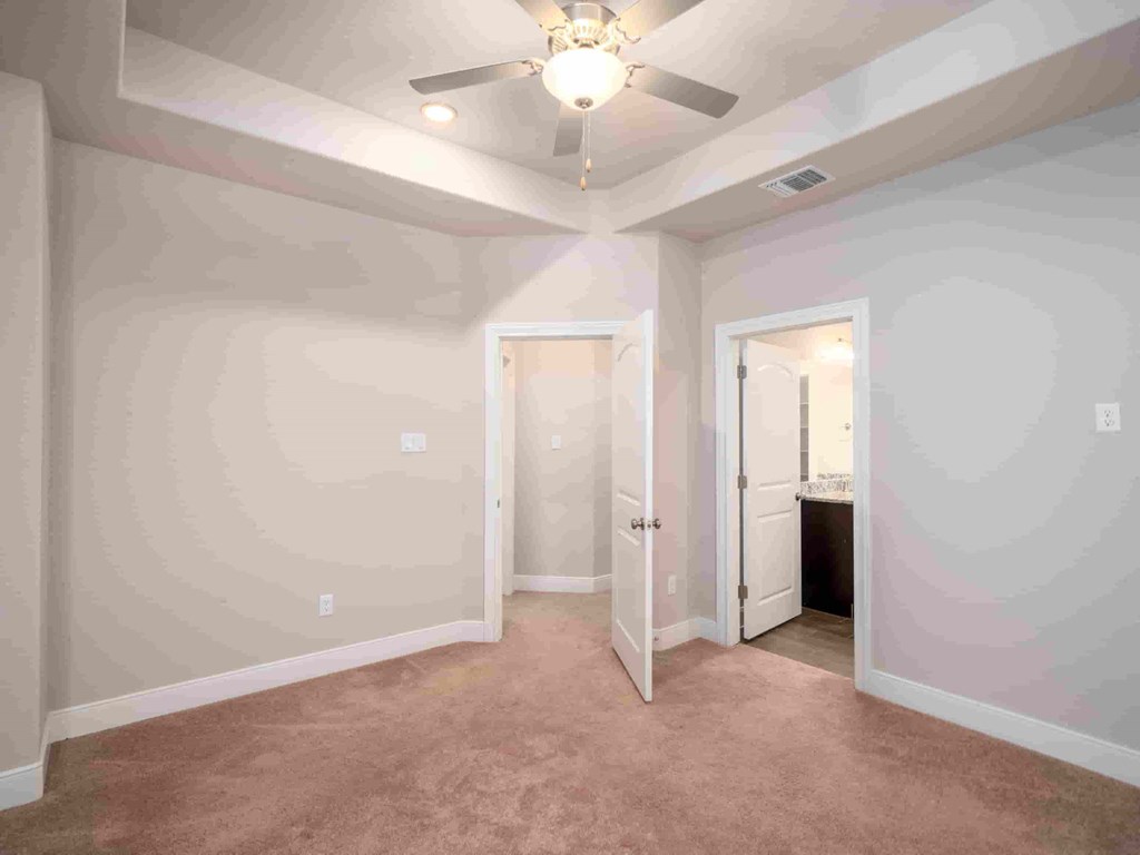 an empty room with a ceiling fan and a door to a bathroom
