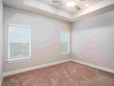 an empty bedroom with a ceiling fan and two windows