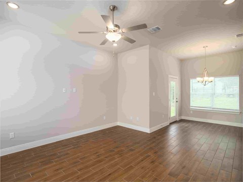 an empty living room with a ceiling fan and wood floors