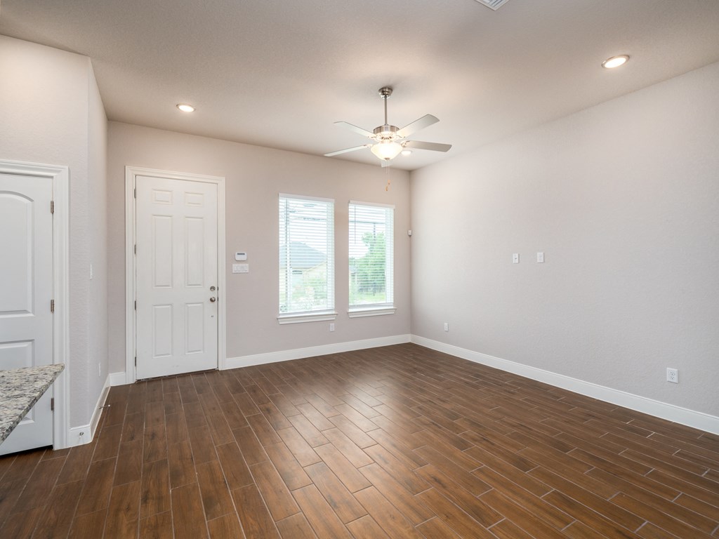 an empty living room with wood flooring and a ceiling fan