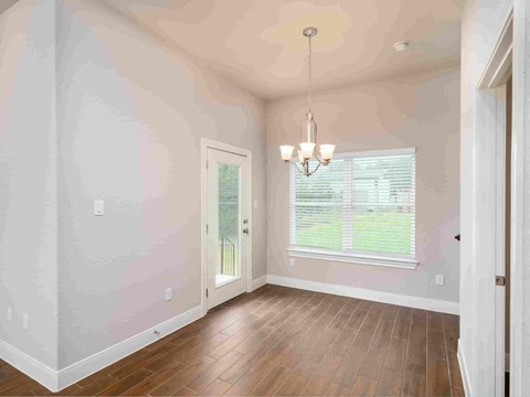 an empty dining room with hardwood floors and a window
