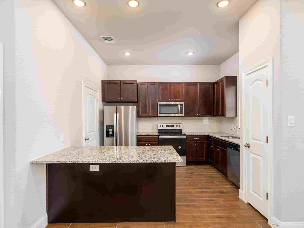 a kitchen with a marble counter top and wooden cabinets
