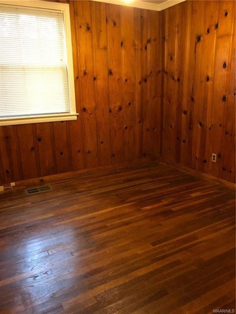 an empty room with wood floors and a window