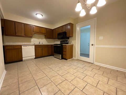 A kitchen with brown cabinets and a white dishwasher.