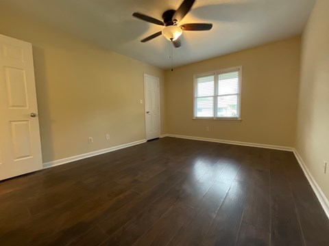 A room with a ceiling fan and wooden flooring.