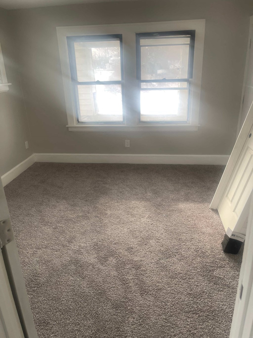 A room with a carpeted floor and a window.