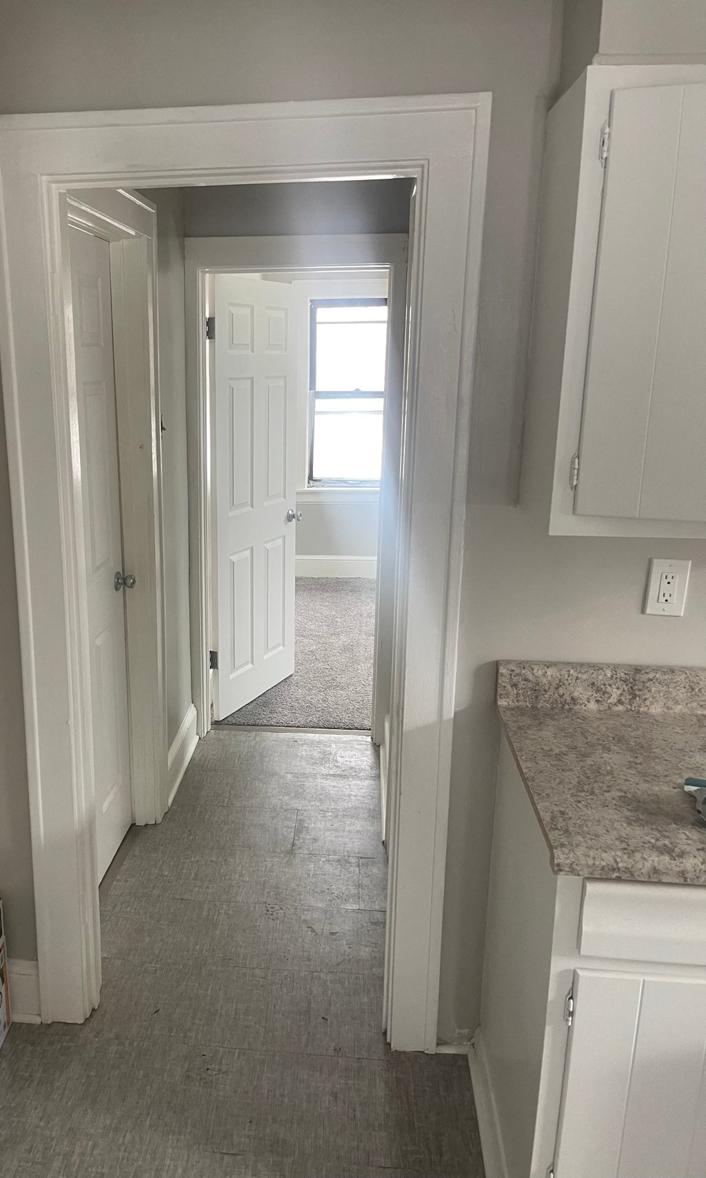 A hallway with white doors and a granite counter.