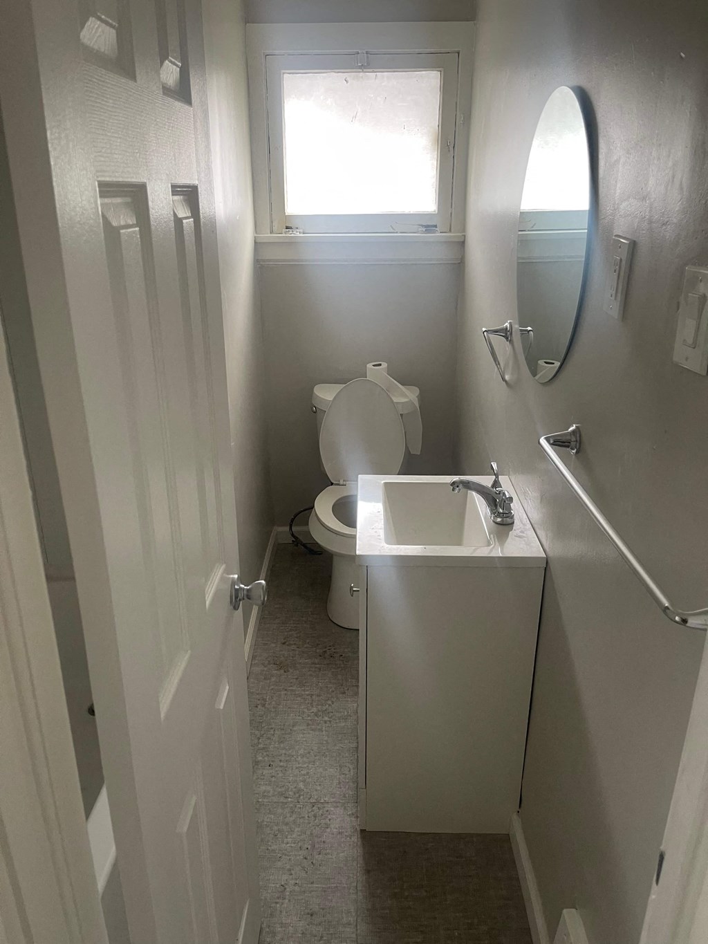 A bathroom with a toilet, sink and mirror.