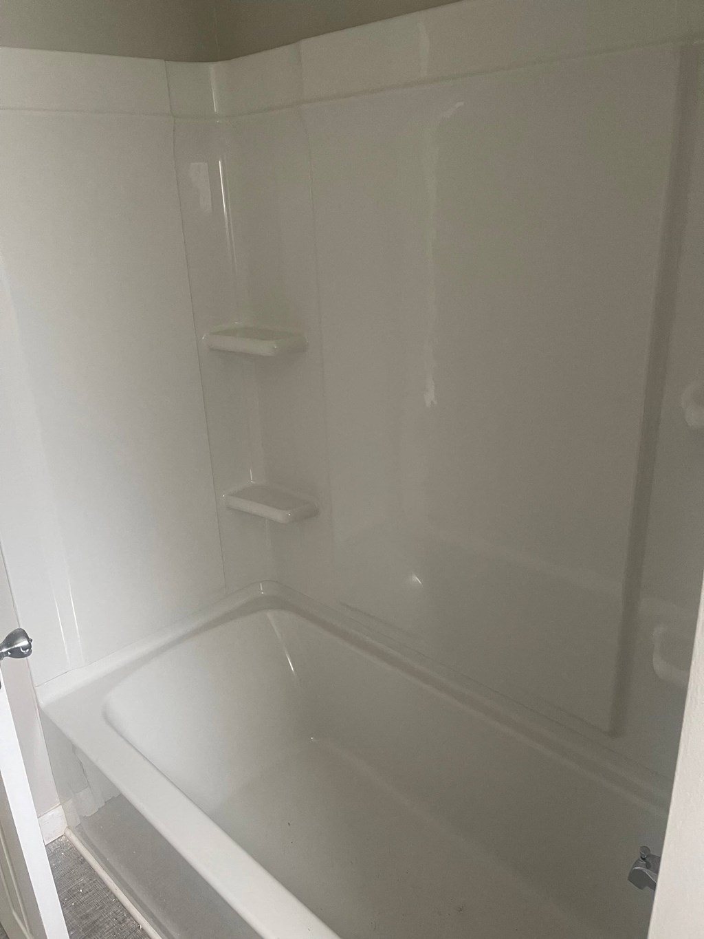 A white bathroom with a tub and a toilet paper holder.