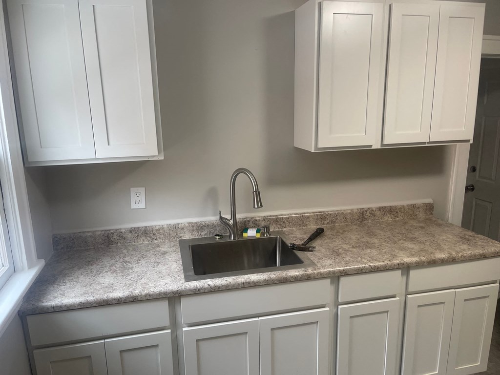 A kitchen with a granite countertop and white cabinets.