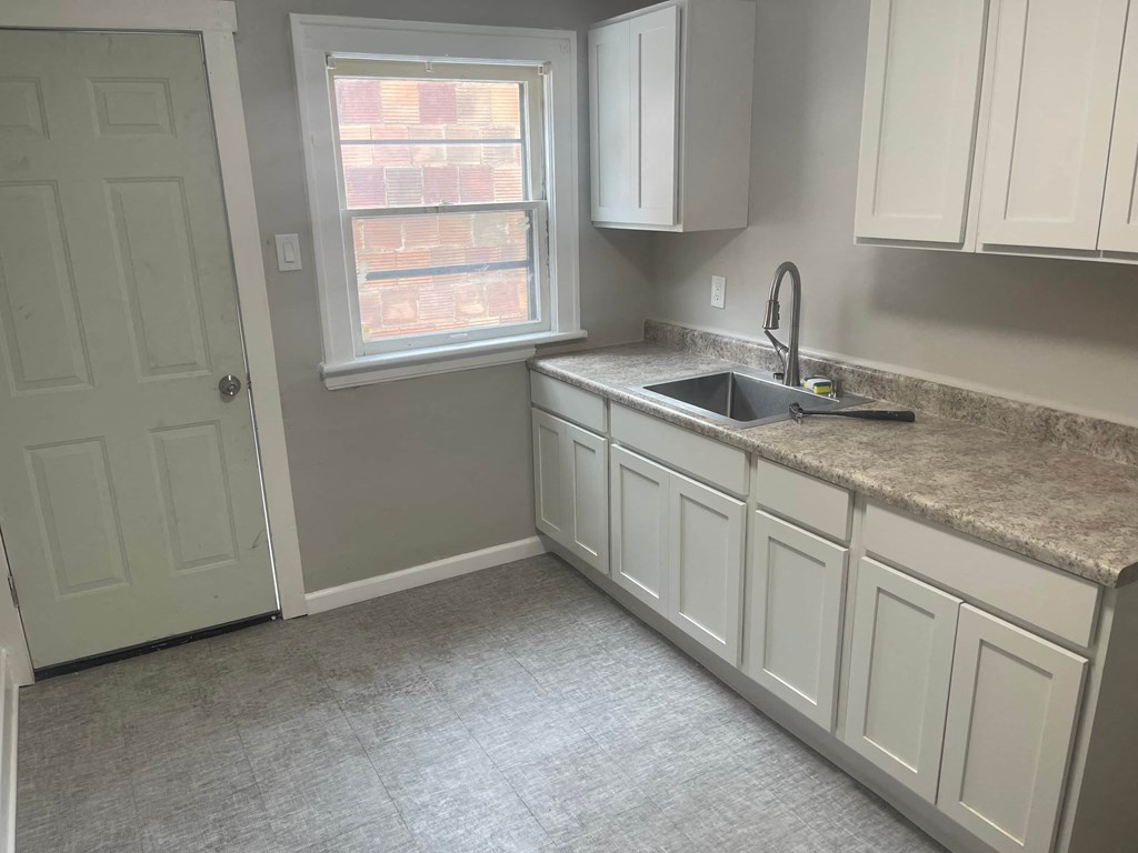 A kitchen with white cabinets and a window.