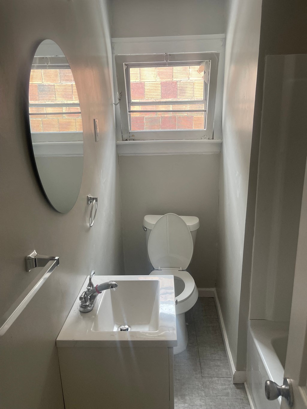 A white toilet sits in a bathroom next to a sink and a window.