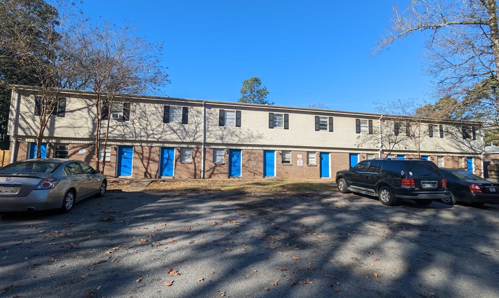 an old brick building with blue doors and cars parked in front