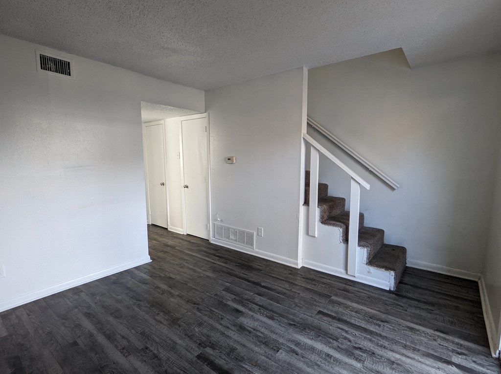 an empty living room with wood floors and white walls