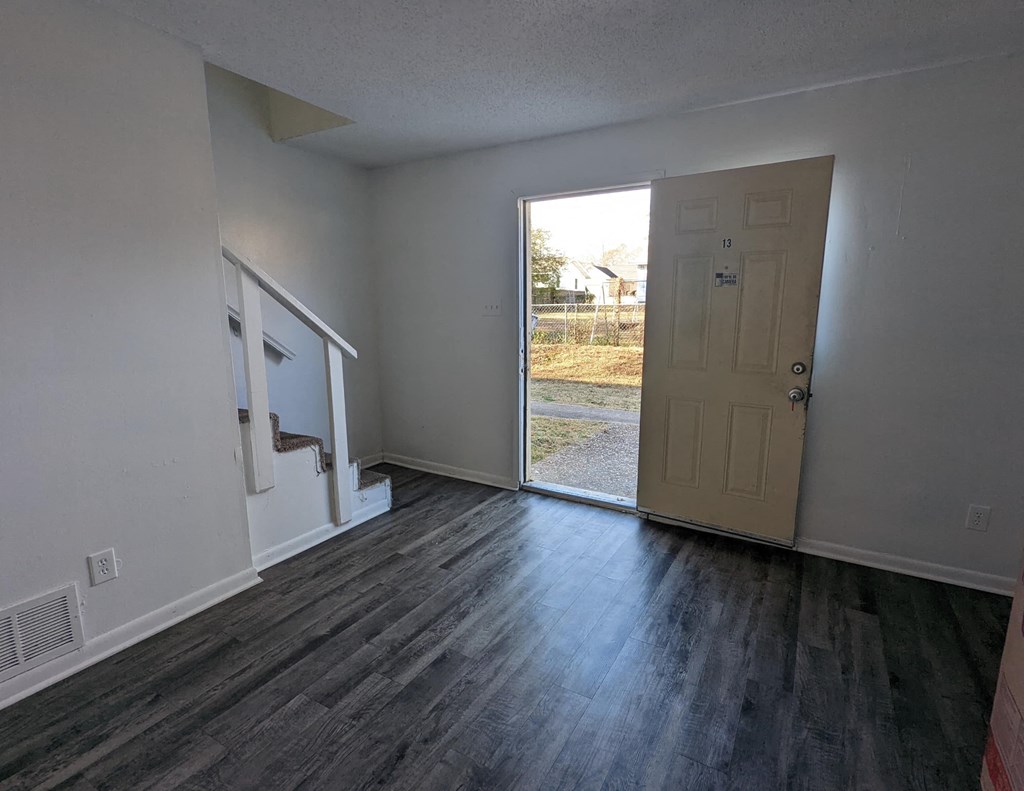 an empty living room with a door to a backyard