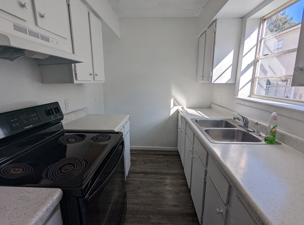 an empty kitchen with white cabinets and a black stove