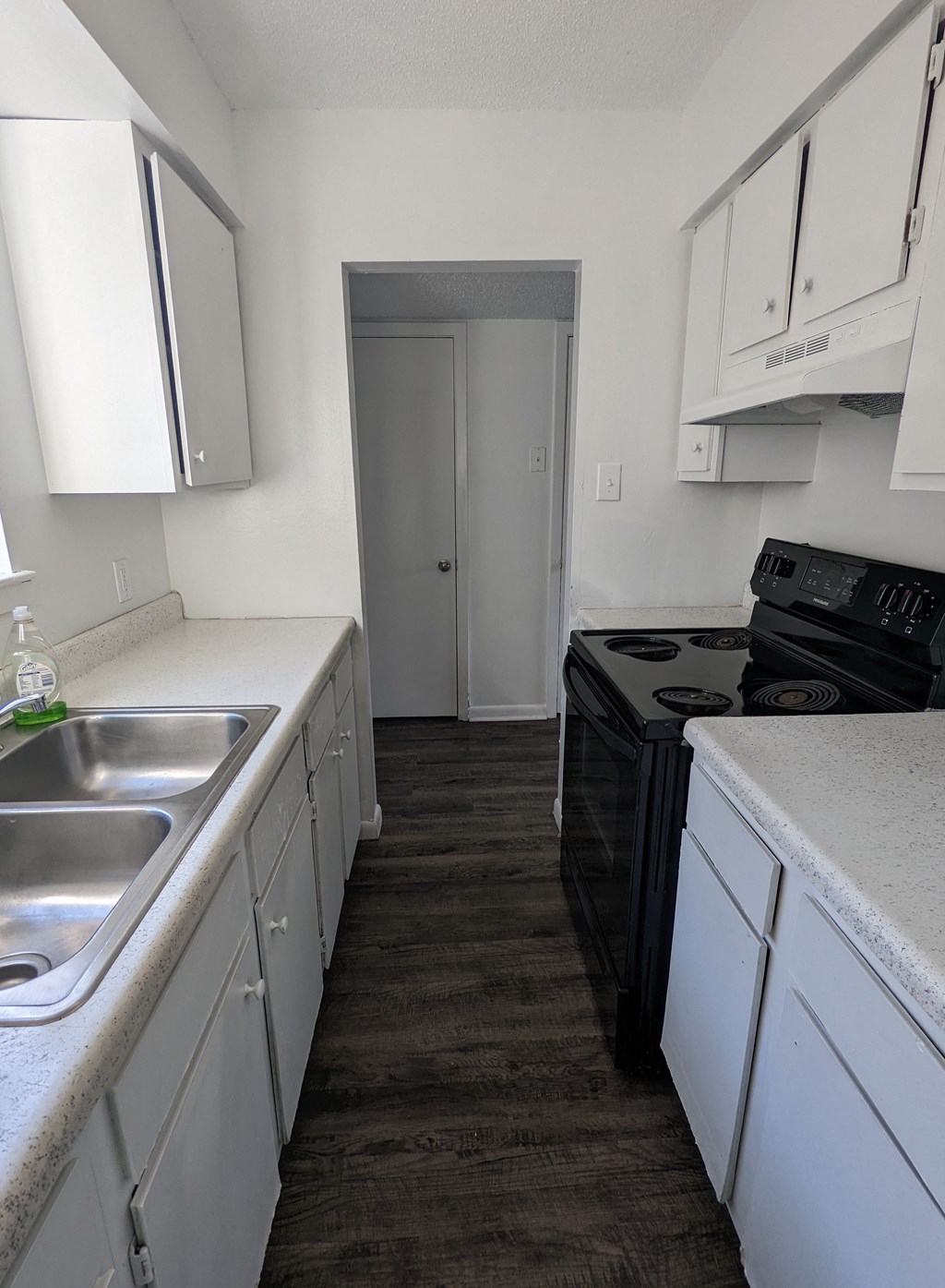 an empty kitchen with white cabinets and a black stove