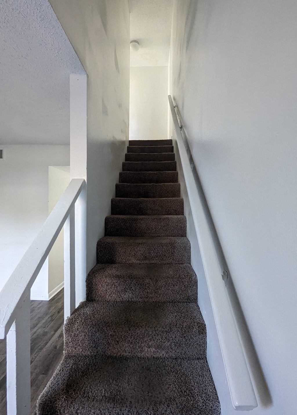a flight of stairs with a white railing and white walls