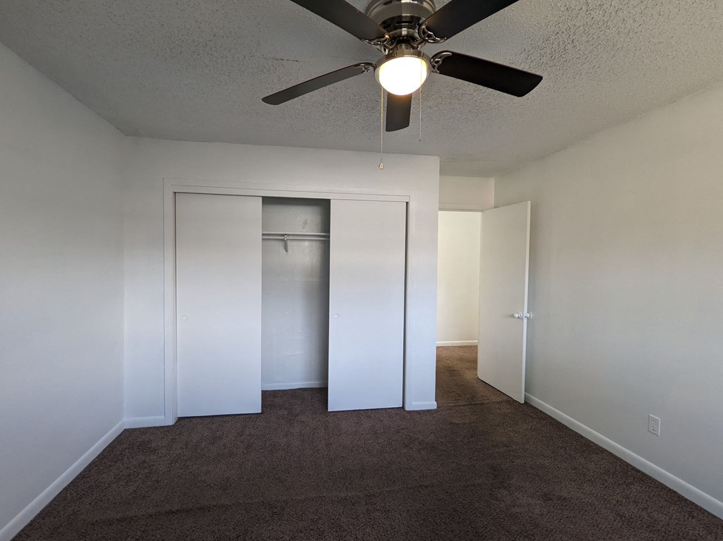 an empty room with a ceiling fan and a closet