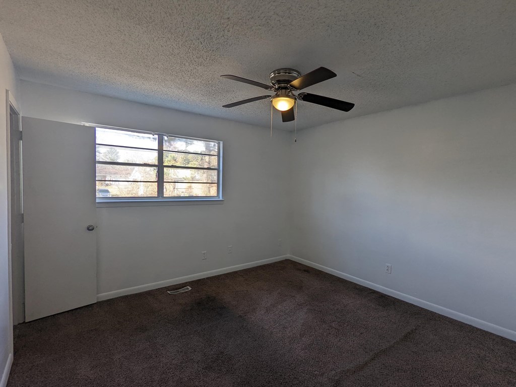 an empty room with a ceiling fan and a window