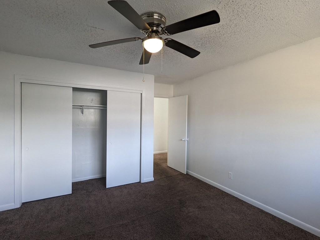 a bedroom with a ceiling fan and a closet