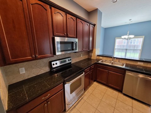 A kitchen with brown cabinets and black countertops.