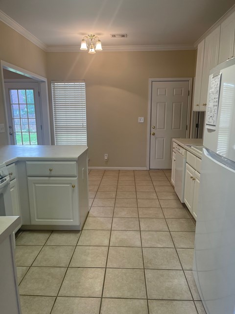 A kitchen with white cabinets and a tiled floor.
