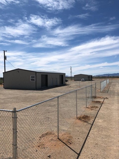 a building in the middle of a field next to a fence