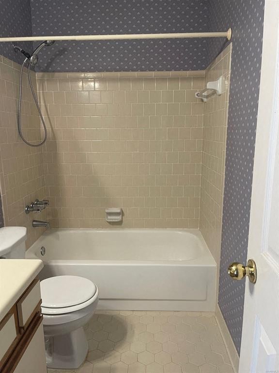 A white toilet sits next to a white bathtub in a bathroom.
