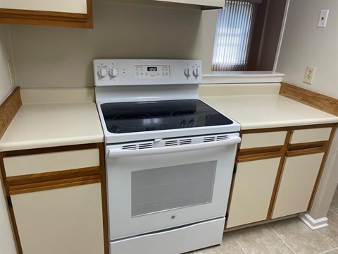 A white stove and oven in a kitchen with wooden cabinets.