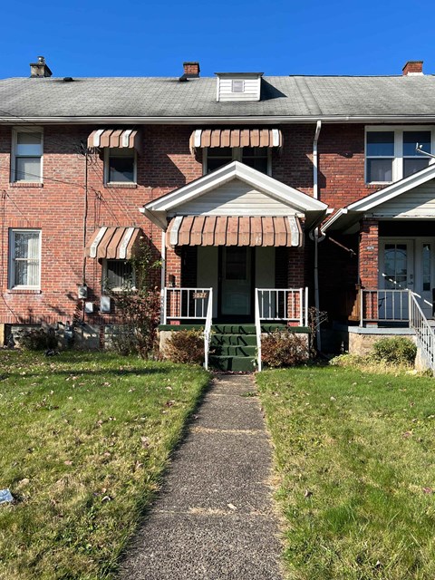 an old brick house with a sidewalk in front of it